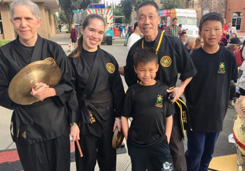 a group three kids and two adults all wearing black with one holding symbols